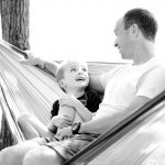 father and son smiling at each other on a hammock