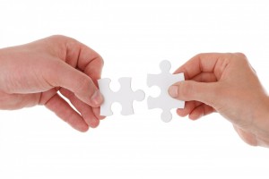 two hands fitting puzzle pieces together